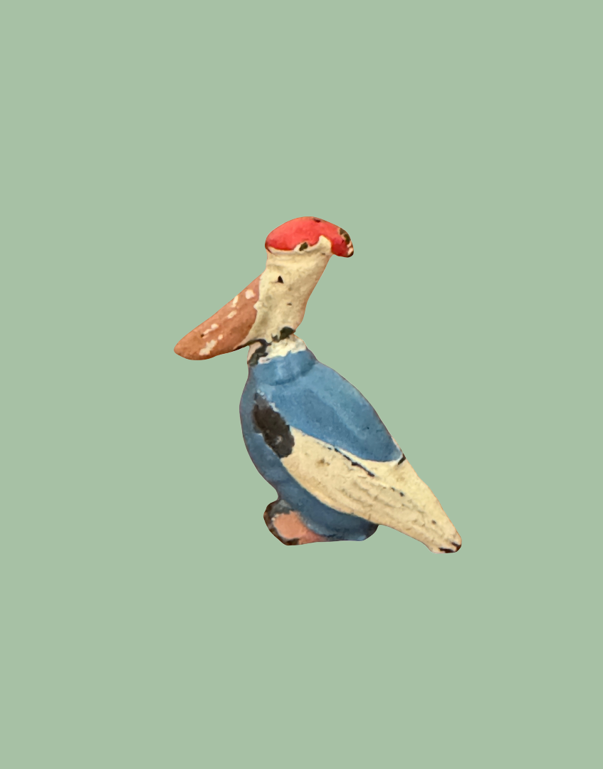 side view of brightly painted blue, pink and white dressed pelican lead figurine 