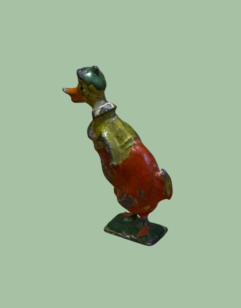 Side view of antique lead duck figure brightly painted in green, yellow and red