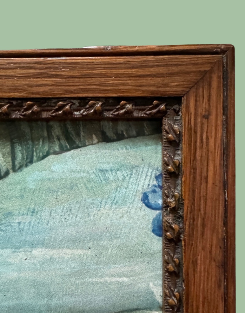 Close-up of an antique-style framed artwork showing a textured blue and gray landscape with a carved dark brown wooden frame.