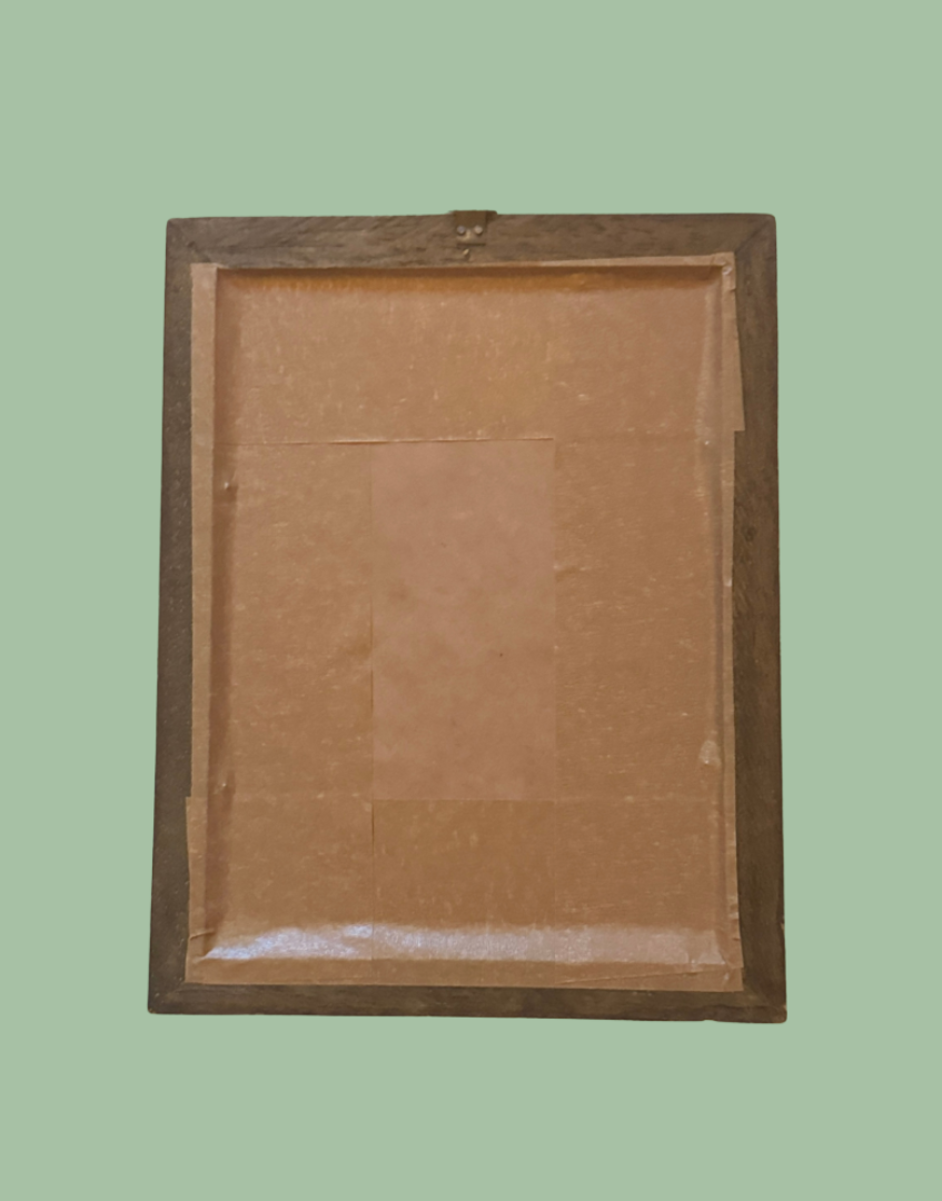 The back of a rectangular wooden picture frame with a brown cardboard backing and mounting hardware, shown against a solid sage green background.