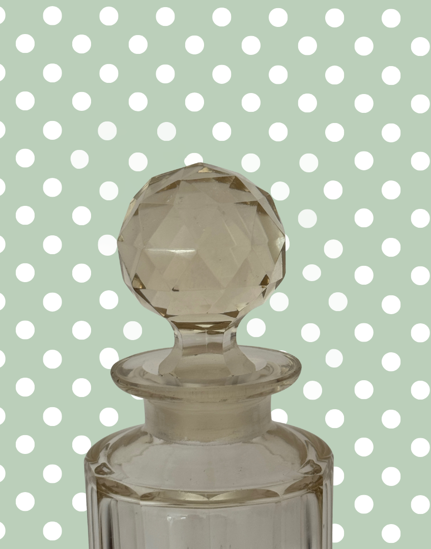Clear glass bottle with a textured stopper on a polka dot background