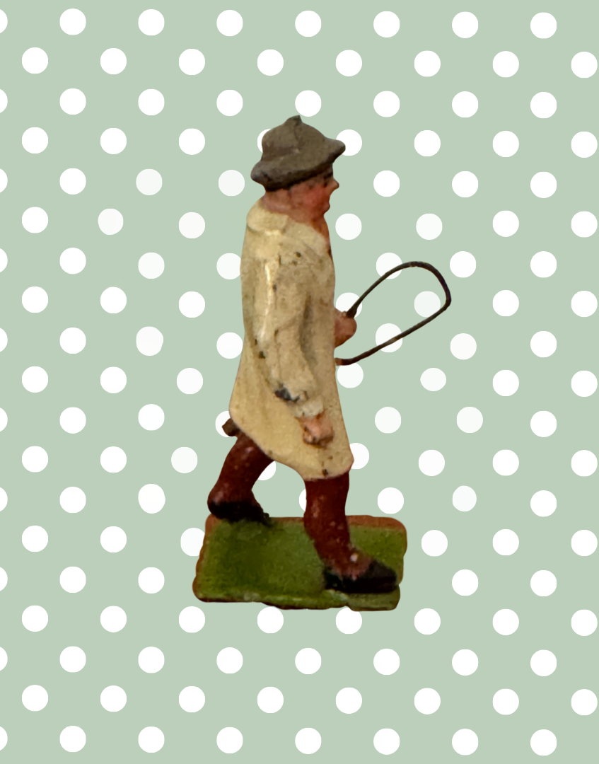 Side view of vintage Britains Carter with Whip figure showing green painted base and traditional farm clothing
