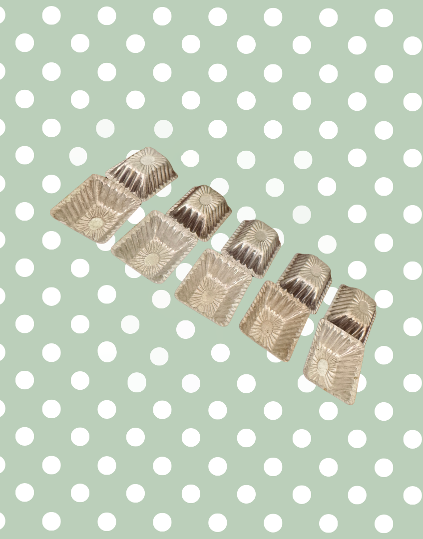 Ten vintage aluminium chocolate moulds displayed together showing rectangular shape, scalloped edges and aged patina
