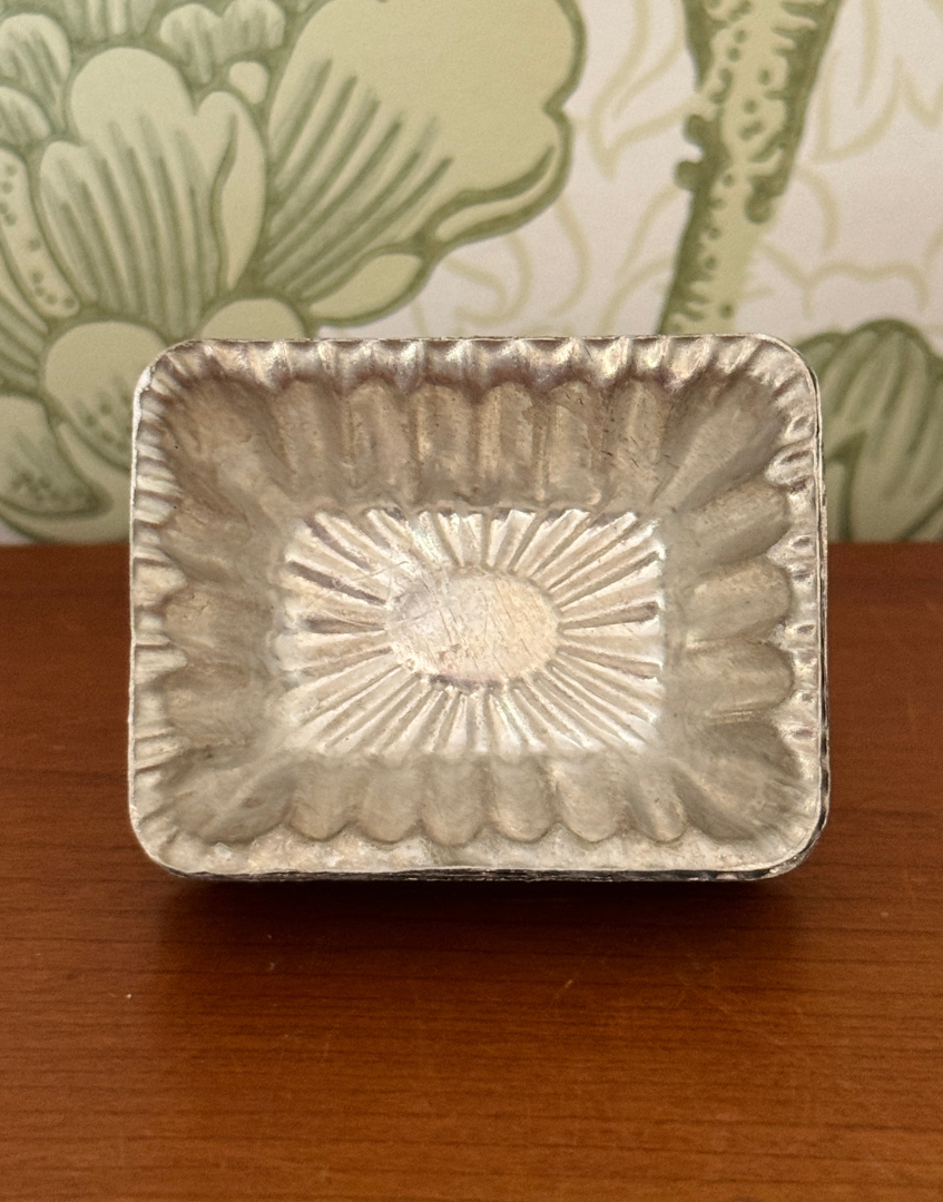 Ten vintage aluminium chocolate moulds displayed together showing rectangular shape, scalloped edges and aged patina