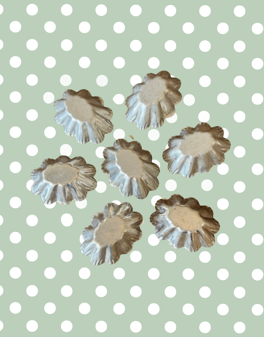 Underside view of seven vintage petit four moulds showing original metal construction and vintage patina
