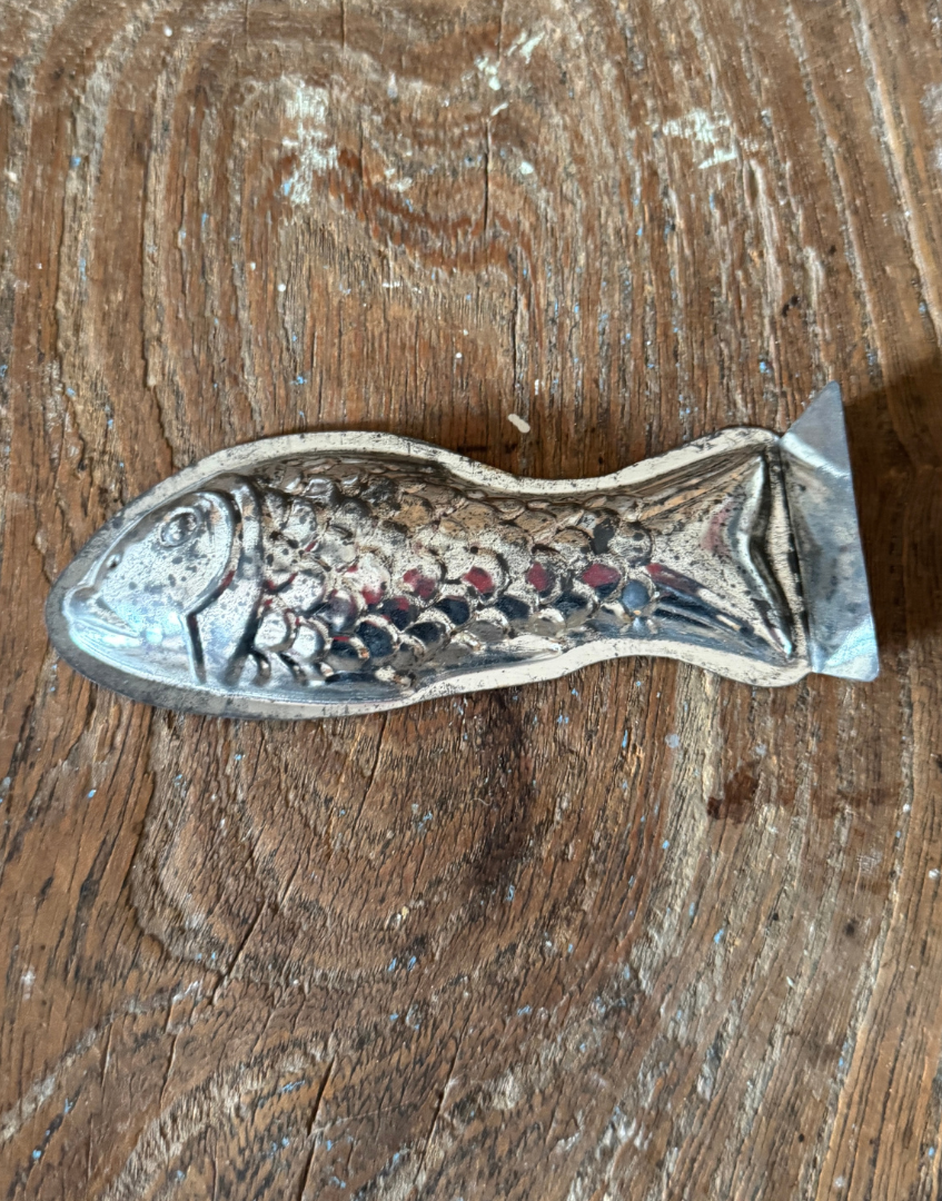 Close view of individual vintage aluminium fish mould with aged patina and decorative kitchenalia appeal