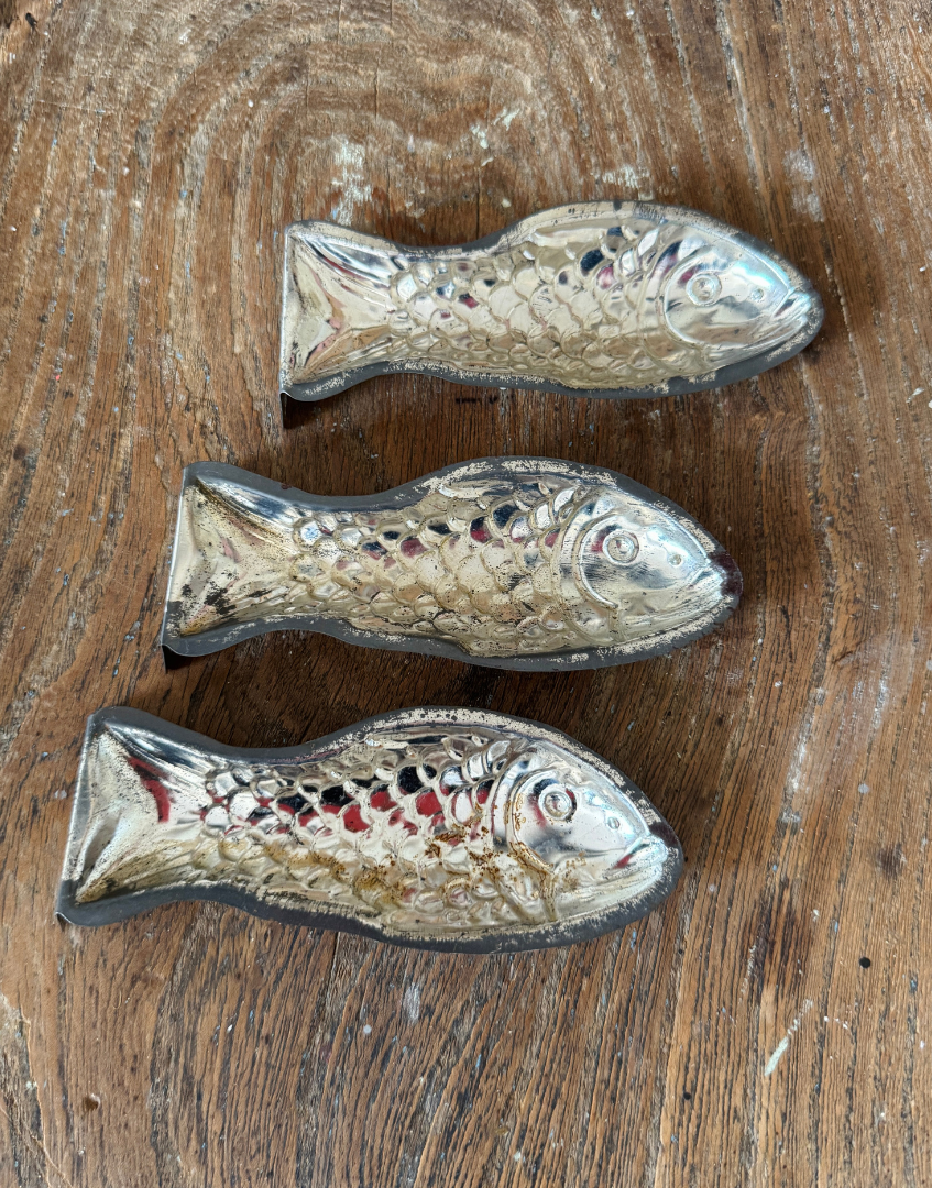Three vintage fish shaped aluminium moulds arranged in a row showing their unusual collectible design
