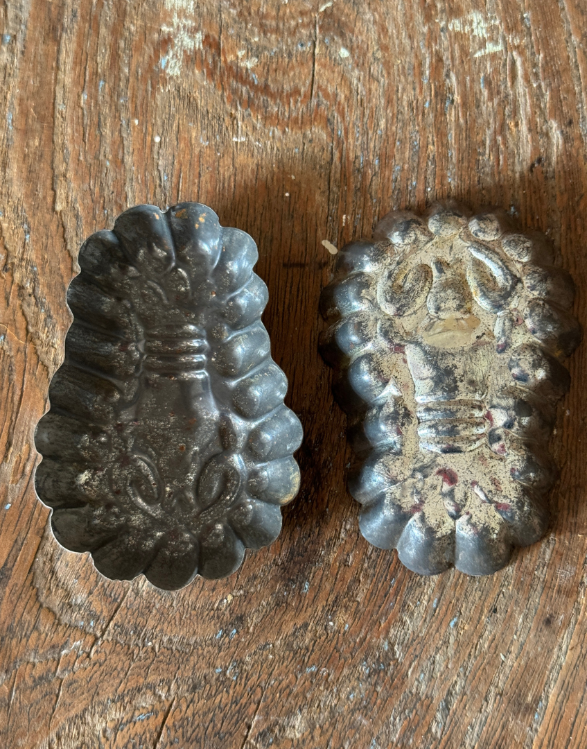Reverse view of vintage lobster shaped tinplate mould pair displayed on textured antique wood showing aged metal character

