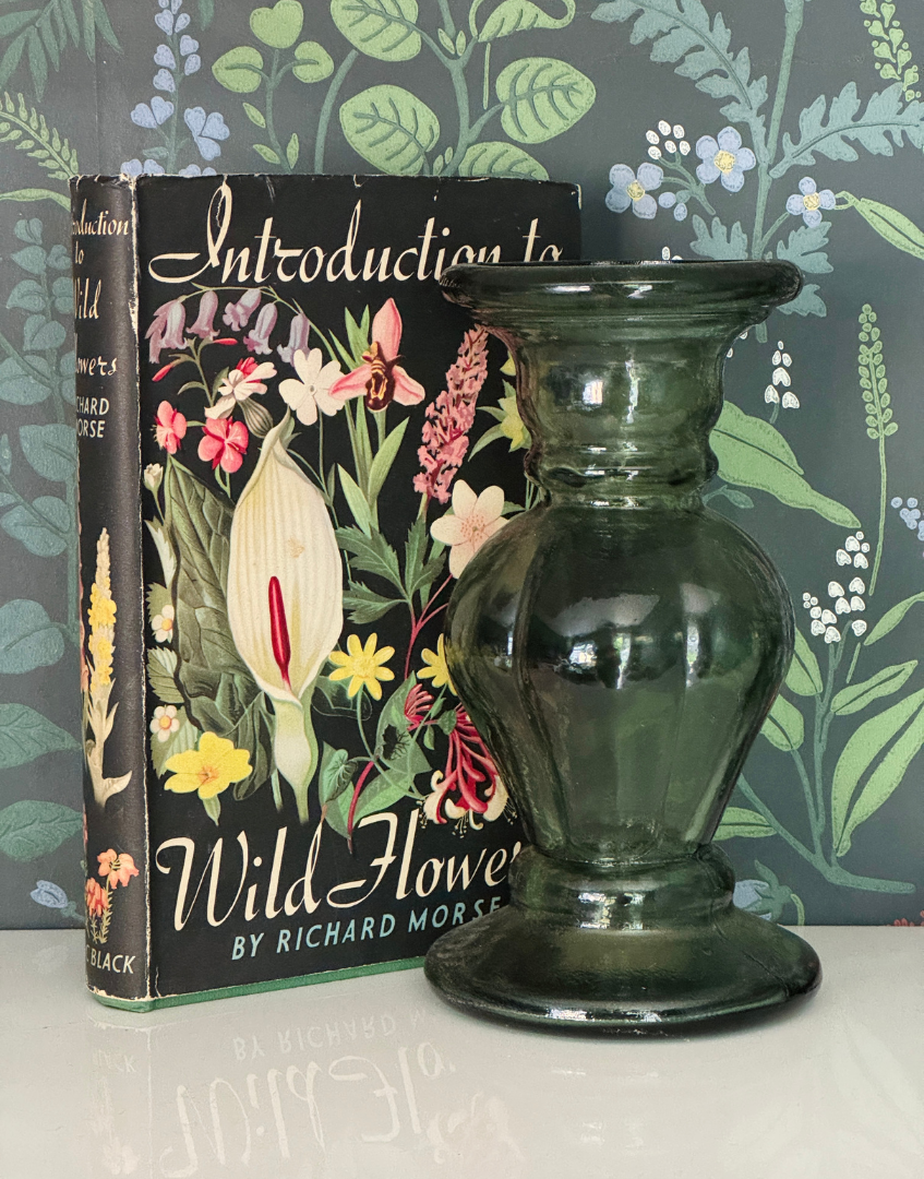 Introduction to Wild Flowers 1949 botanical book styled on a shelf with a green glass candlestick