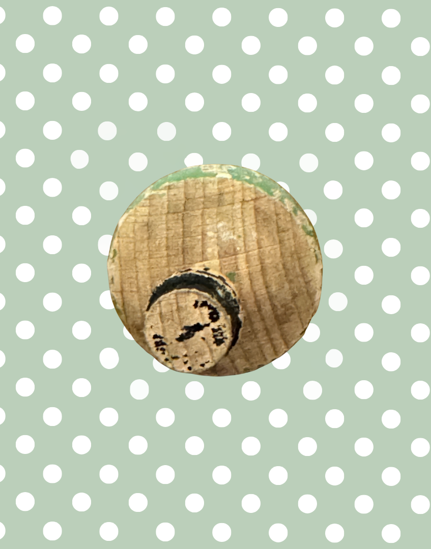 Top view of antique wooden spinning top showing the carved gentleman’s bowler hat and aged painted surface.