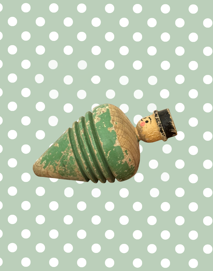 Right side view of antique carved gentleman spinning top showing the profile, painted details and weathered surface.