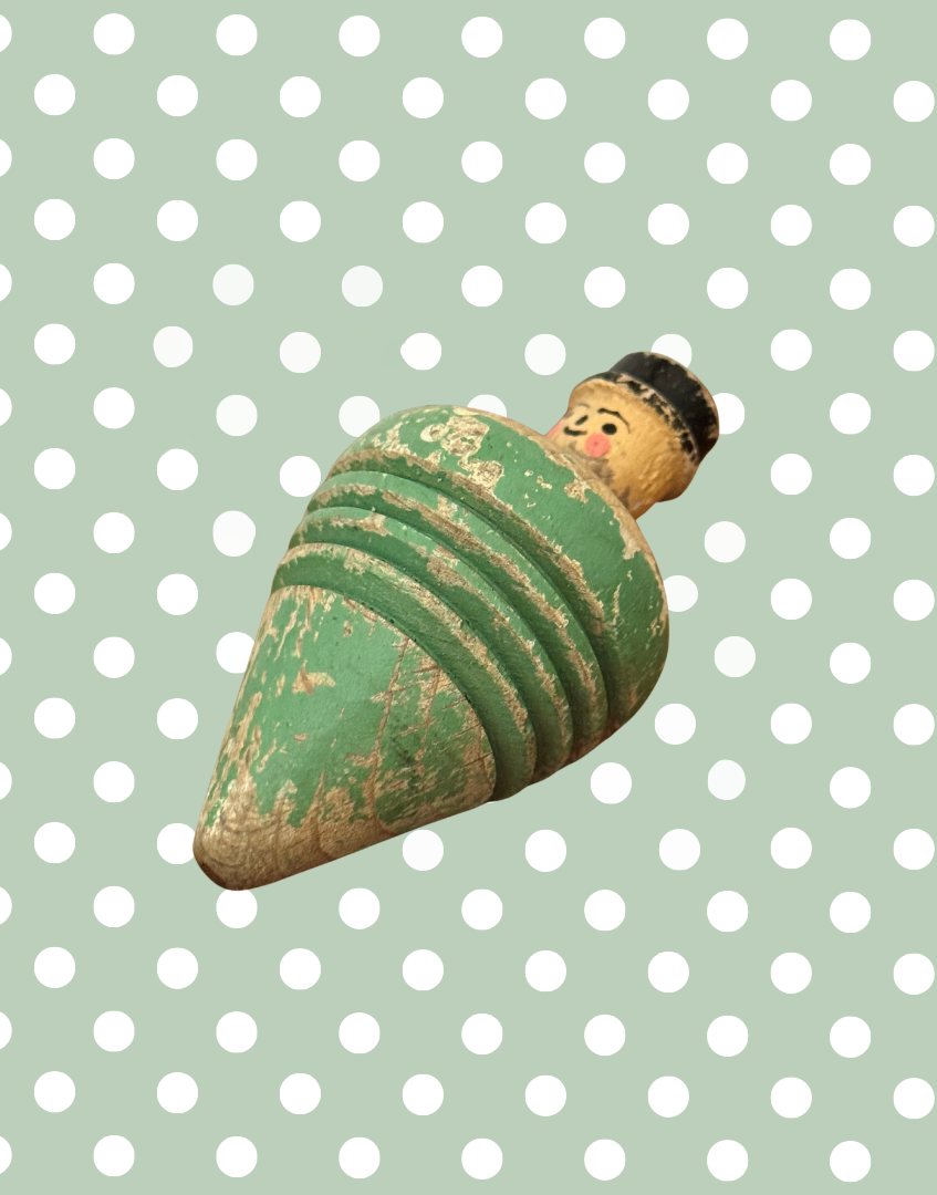 Front view of antique wooden spinning top with a hand carved gentleman’s head, painted facial features and bowler hat.