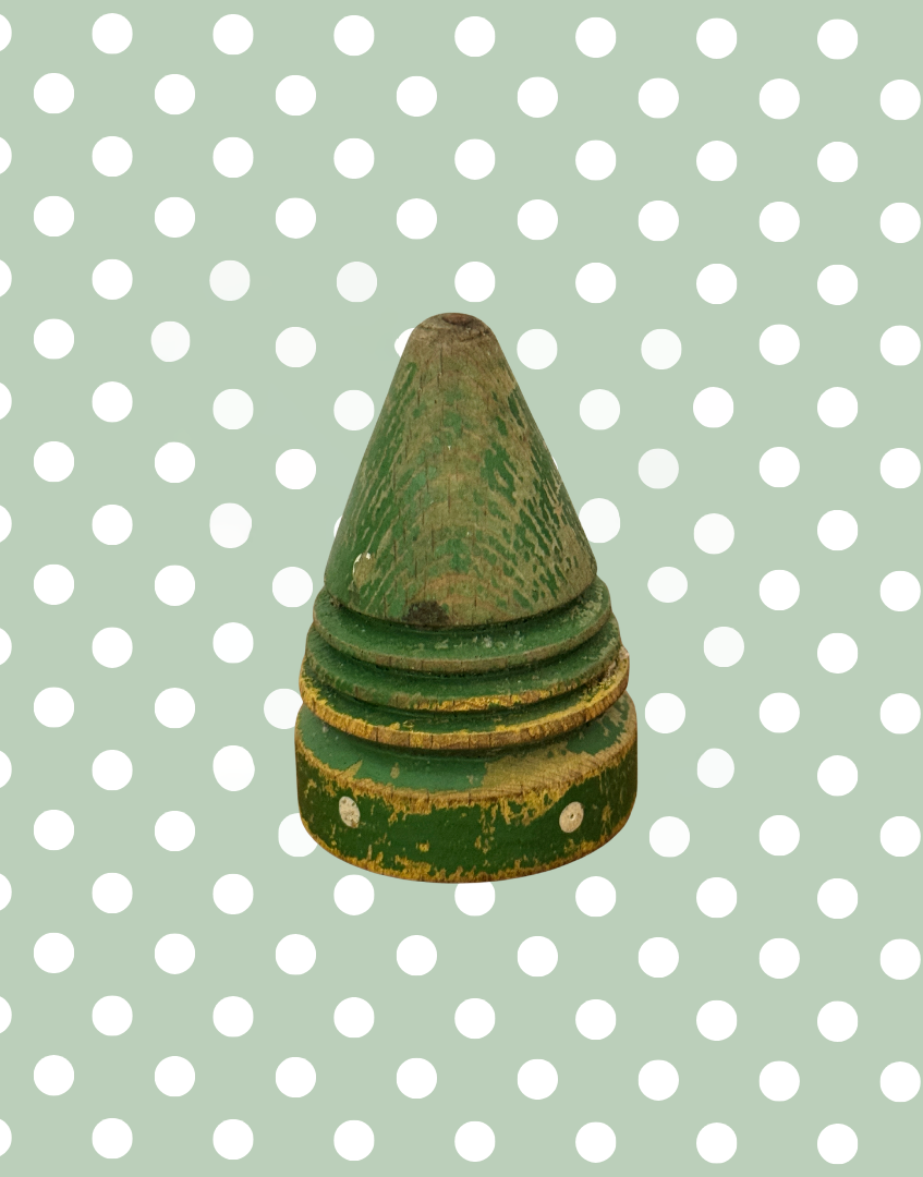 Front view of antique wooden spinning top with original painted polka dot decoration and weathered surface.