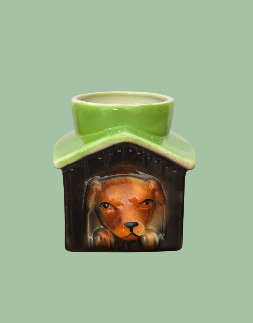 Vintage Tony Wood dog in kennel egg cup with a brown dog, black kennel and apple green roof against a sage background.