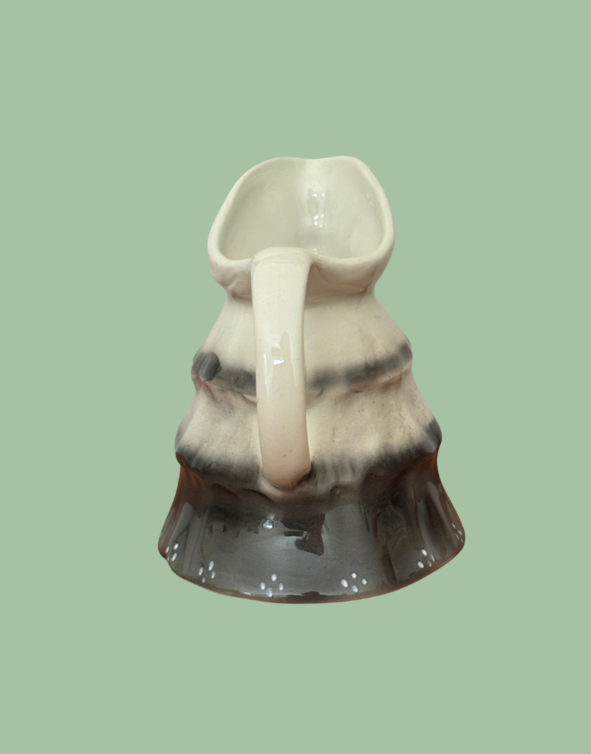 Rear view of Tony Wood Little Old Lady creamer showing the cream handle and interior, shaded shawl and dark dotted skirt.