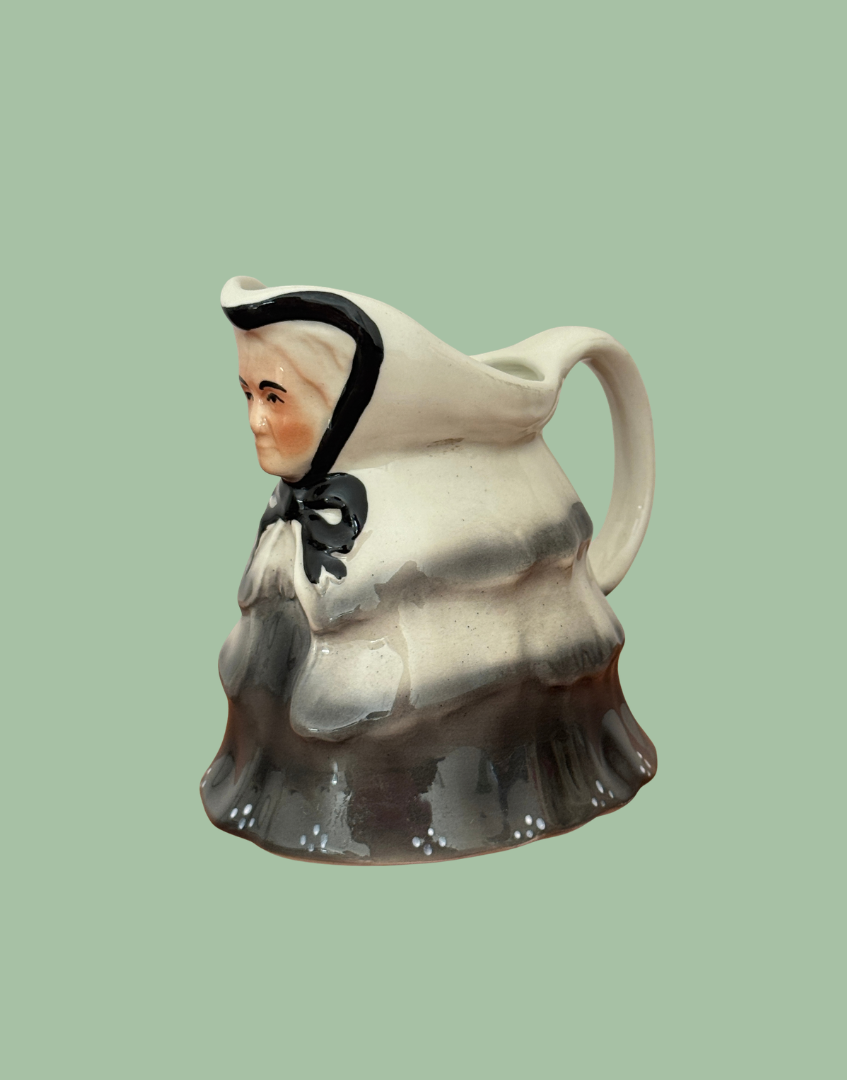 Opposite angled view of Tony Wood Little Old Lady creamer showing the black-edged hood, shaded grey shawl and dotted skirt.