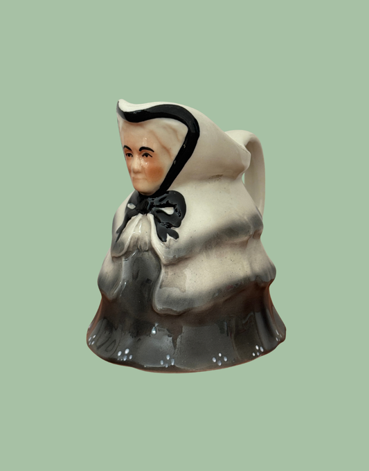 Vintage Tony Wood Little Old Lady milk jug in black, grey and cream, shown at an angle with its curved handle visible.