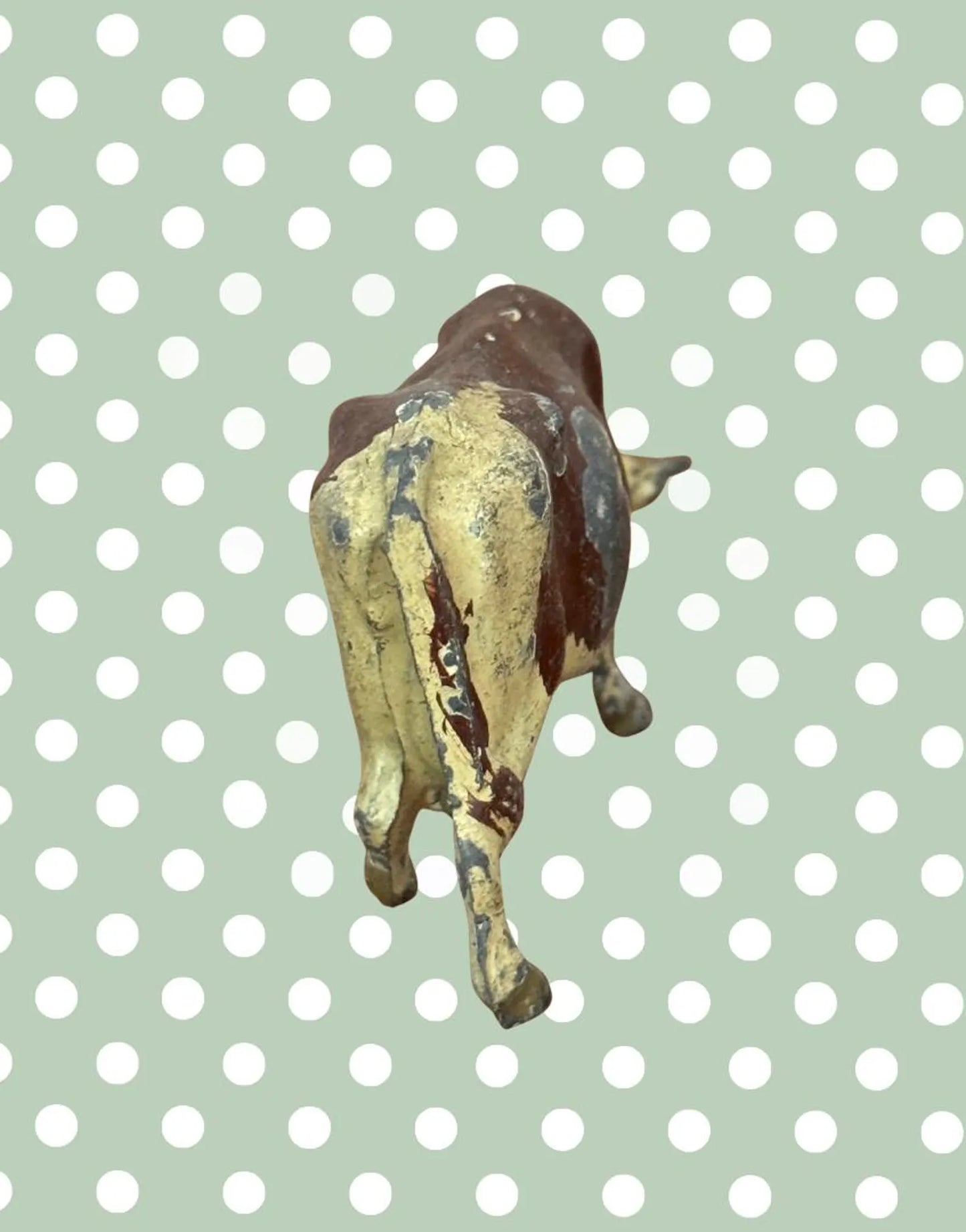 Rear view of small figurine of a vintage lead cow toy