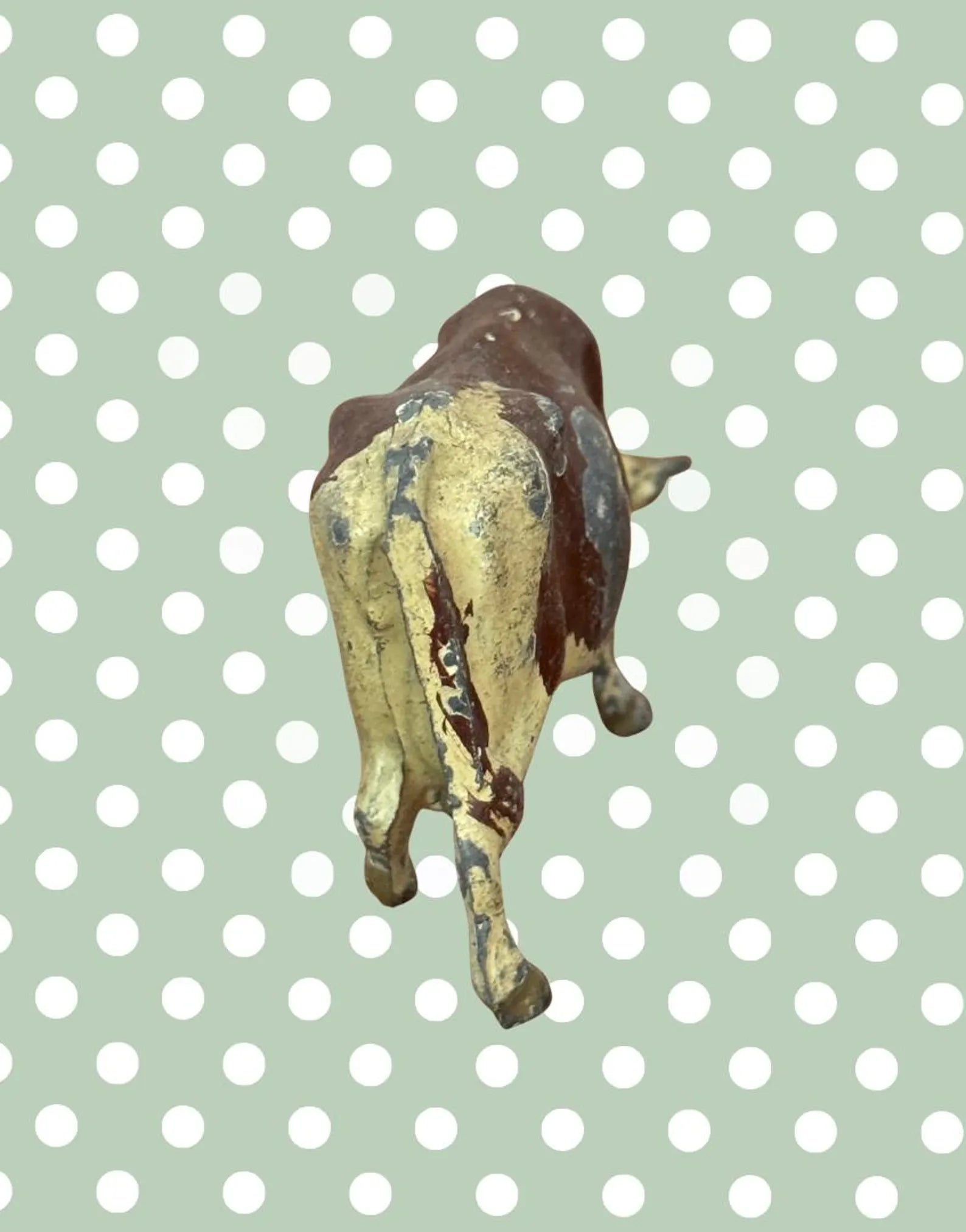Rear view of small figurine of a vintage lead cow toy