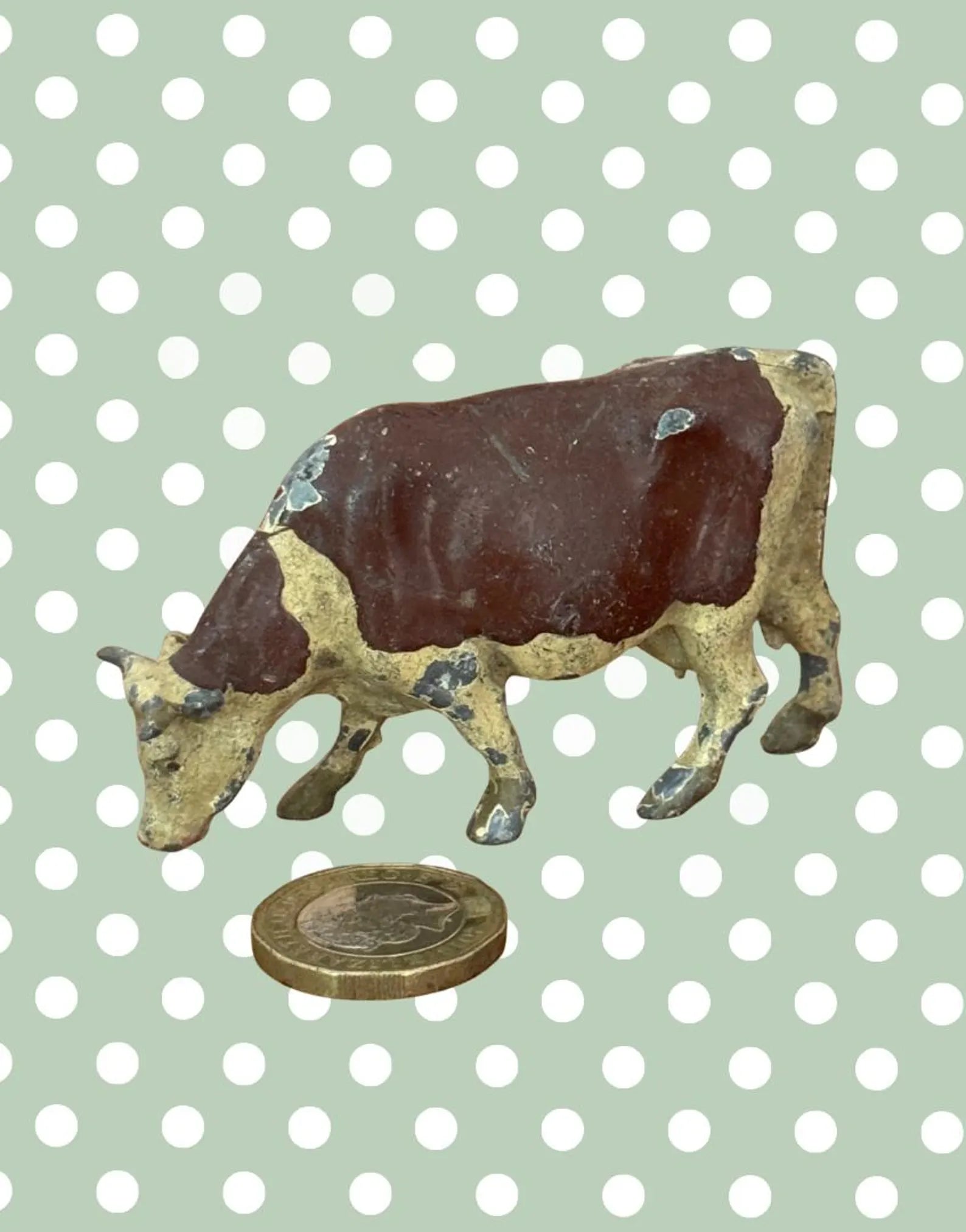 britains farm series vintage lead cow fihurine next to a pound coin for scale