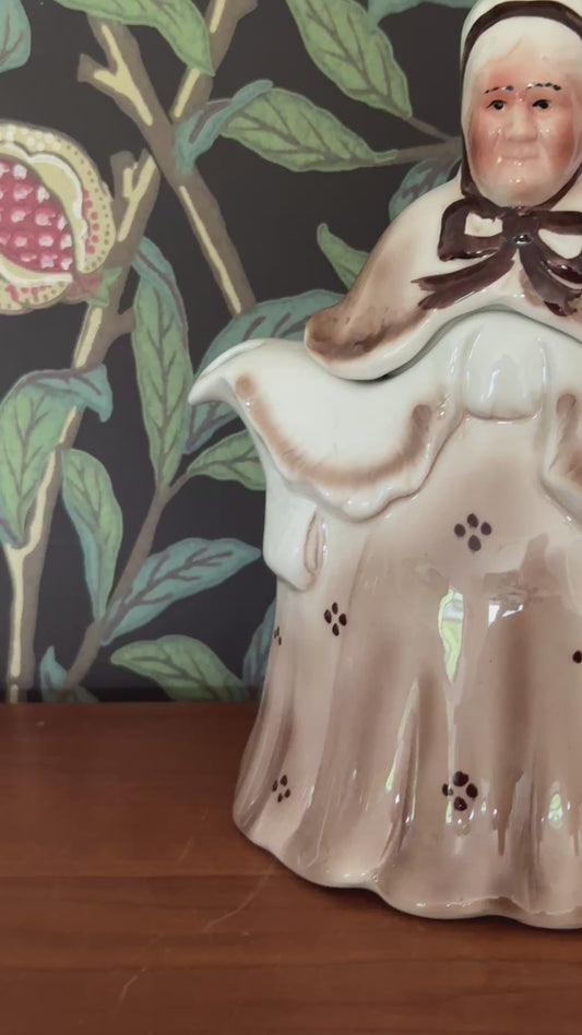 Front view of Tony Wood Little Old Lady teapot in brown Staffordshire pottery with hand painted facial features and patterned bonnet