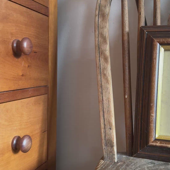 Cottage core style bedroom interior with woodd furniture and decorative asian inspired crane vintage framed gold and red print placed on chair.
