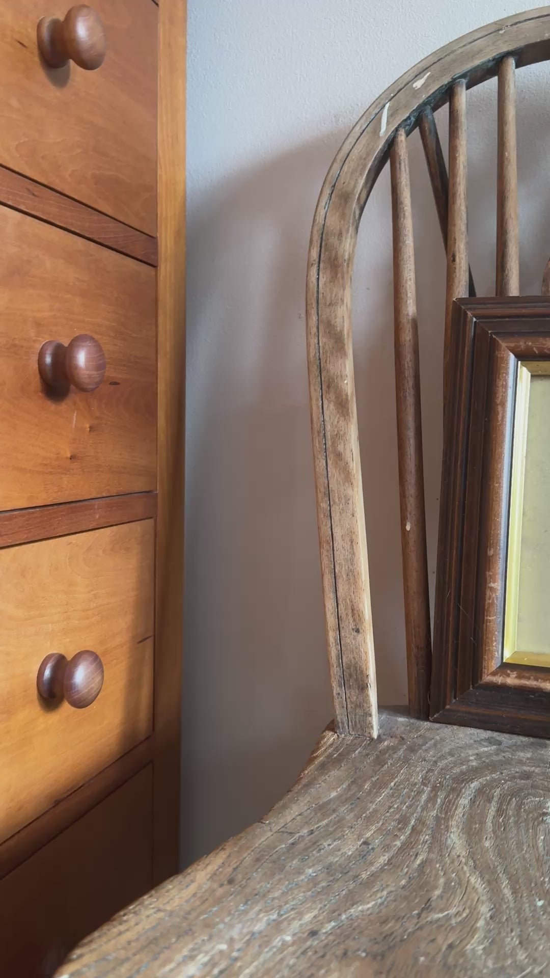 Cottage core style bedroom interior with woodd furniture and decorative asian inspired crane vintage framed gold and red print placed on chair.
