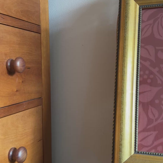 Anitque gold framed William Morris framed print placed on old wood chair seat.