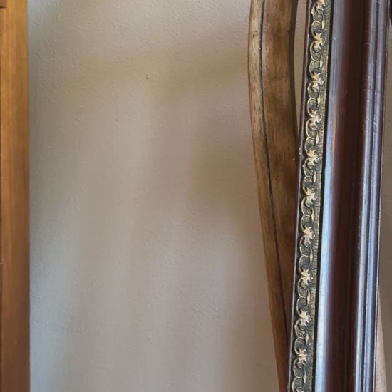 Video showing antique decorative wood and metal picture frame with aged finish and ornate detailing on vintage wooden chair.