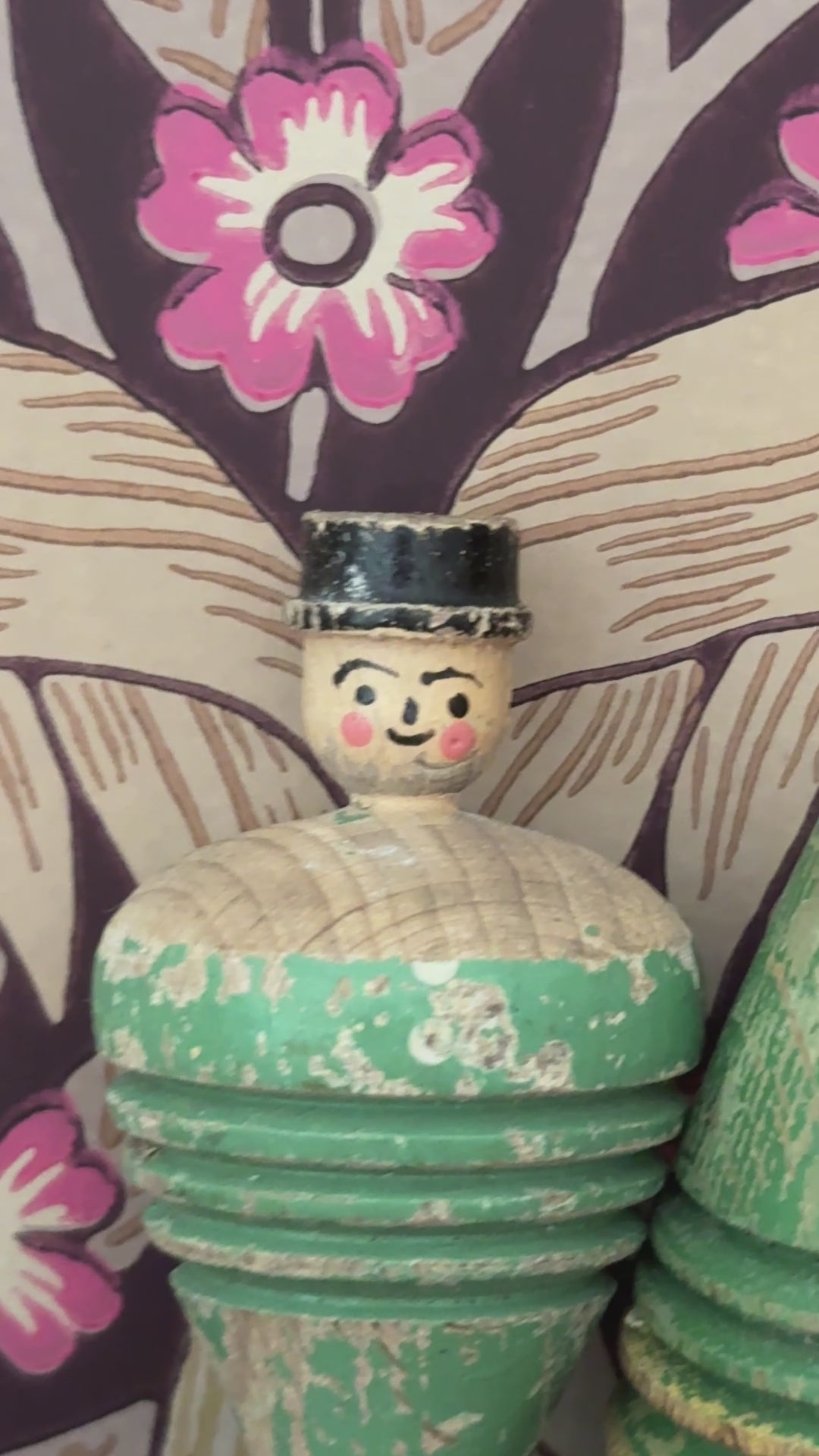 Pair of antique wooden spinning tops styled on a wooden shelf against William Morris Pimpernel wallpaper, featuring a carved gentleman and painted polka dot design.