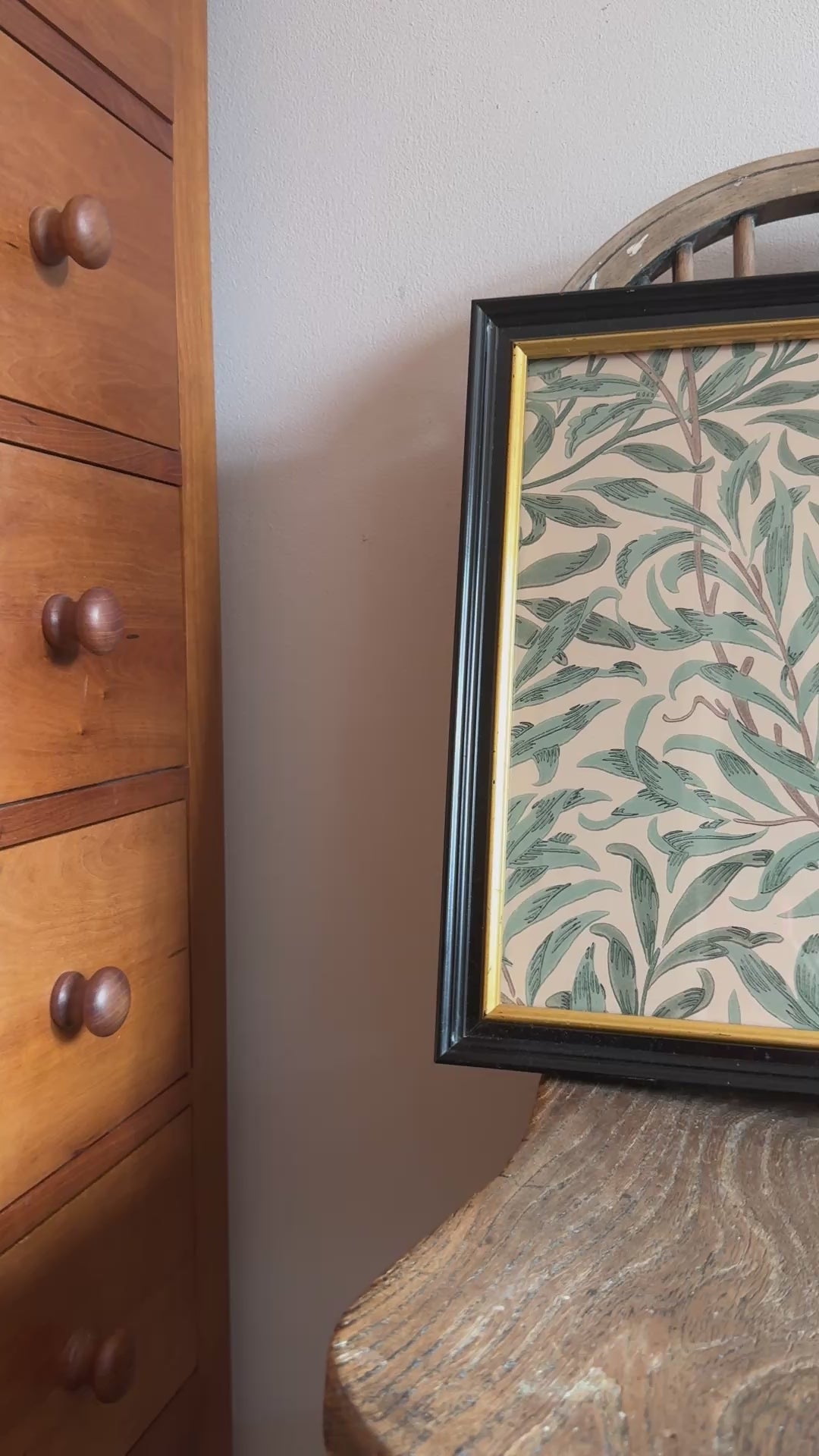 Black and gold almost square framed William Morris Willow Boughs Privet bitanical print placed on seat of an antique wooden chair.