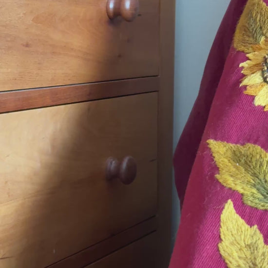 Antique embroidered pelmet styled over an antique chair, showing the asymmetric shape and richly coloured sunflower and foliage embroidery.