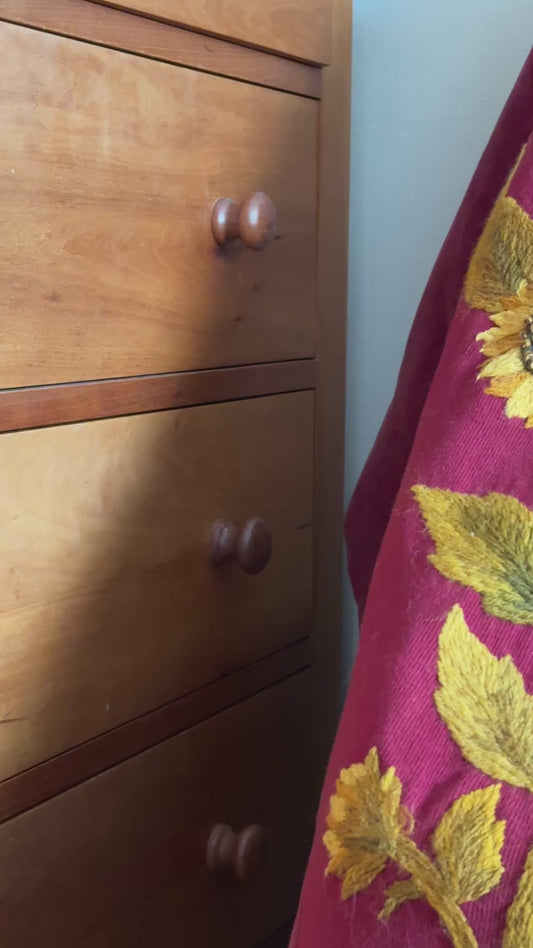 Antique embroidered pelmet styled over an antique chair, showing the asymmetric shape and richly coloured sunflower and foliage embroidery.